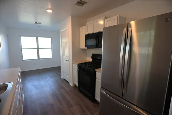 a kitchen with stainless steel appliances a refrigerator and wooden floor