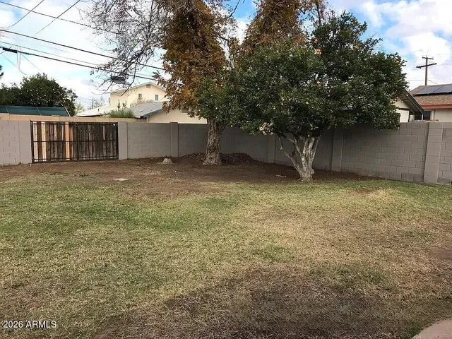 a backyard of a house with large trees and a barn