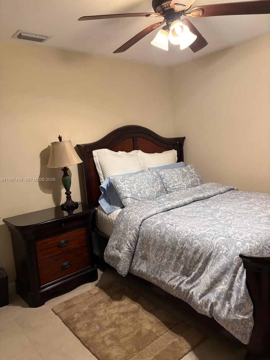 13361 Southwest 88th Terrace, Unit G Miami, FL 33186 - Photo 3 of 4 a bedroom with a bed and a chandelier