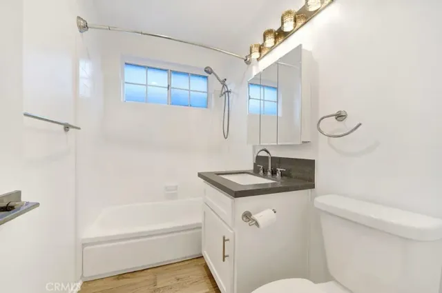 a bathroom with a granite countertop sink a toilet and shower