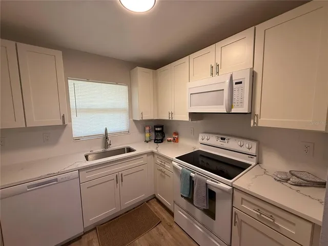 a kitchen with cabinets appliances a sink and a window