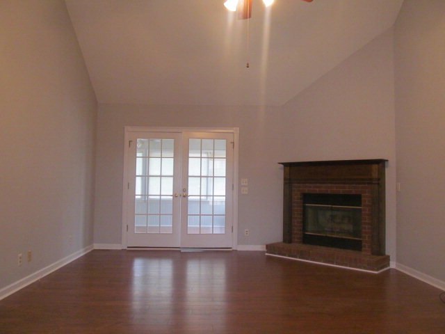 5016 Hartley Bridge Road Macon, GA 31216 - Photo 3 of 27 an empty room with wooden floor fireplace and windows