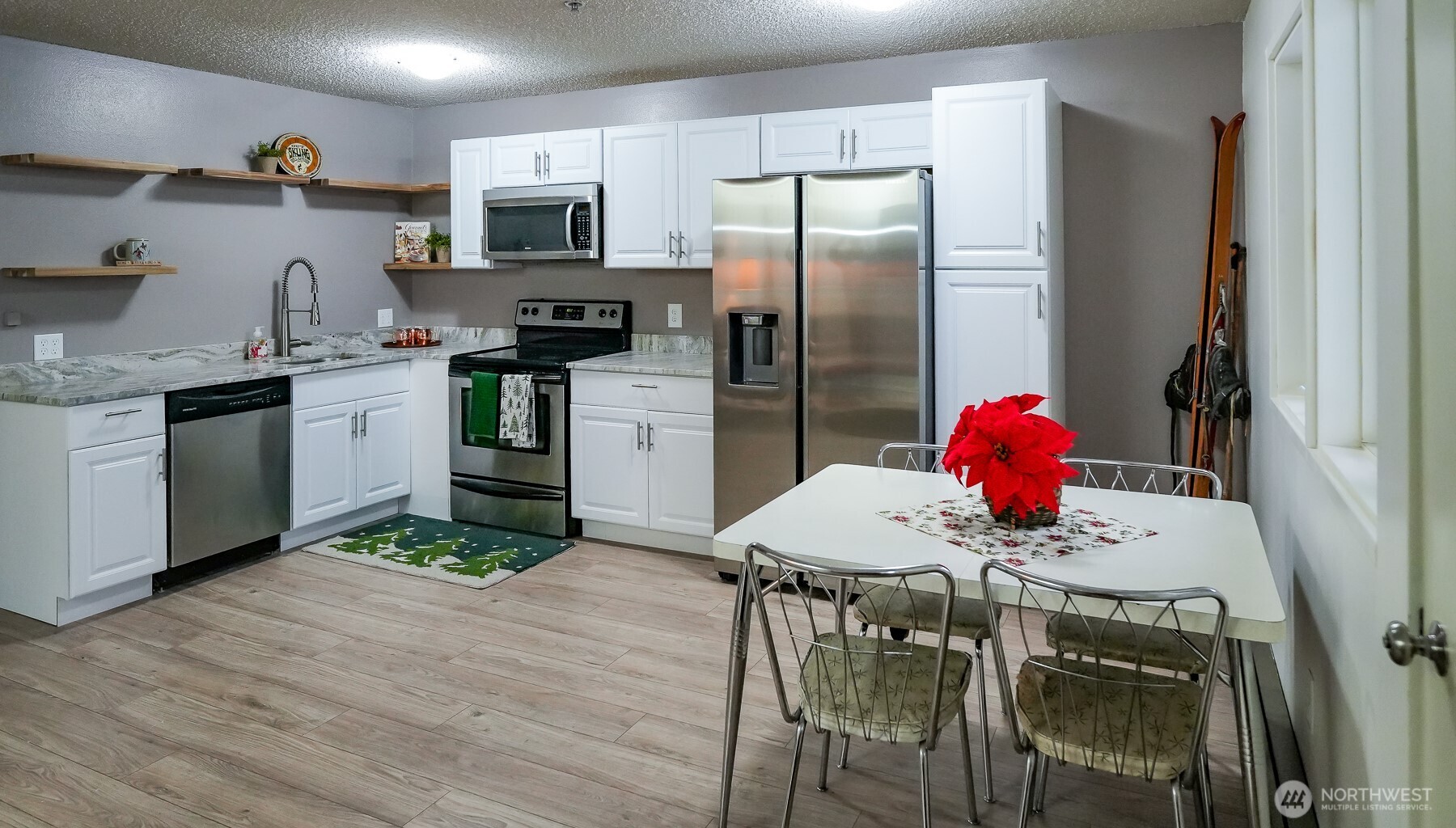 220 Tanner Way, Unit 206 Snoqualmie Pass, WA 98068 - Photo 17 of 37 a kitchen with stainless steel appliances kitchen island granite countertop a refrigerator a stove a microwave oven a sink and a dining table with wooden floor