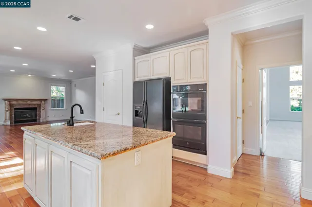 a large kitchen with stainless steel appliances granite countertop a refrigerator a sink dishwasher a stove and white countertops with wooden floor