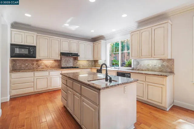 a view of kitchen with granite countertop white cabinets and sink