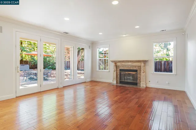 an empty room with wooden floor fireplace and windows