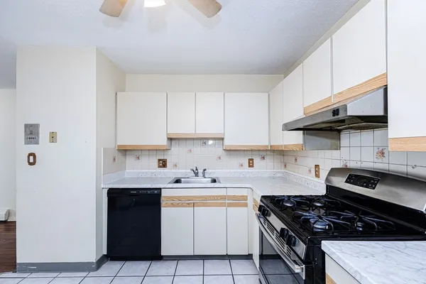 a kitchen with granite countertop a sink a stove and cabinets