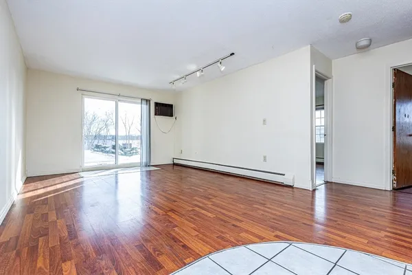 a view of an empty room with wooden floor and a window