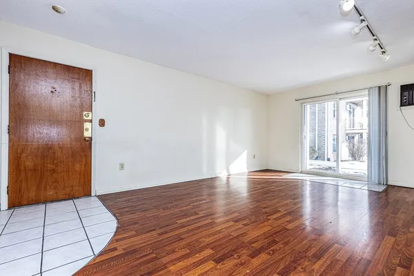 a view of an empty room with wooden floor and a window