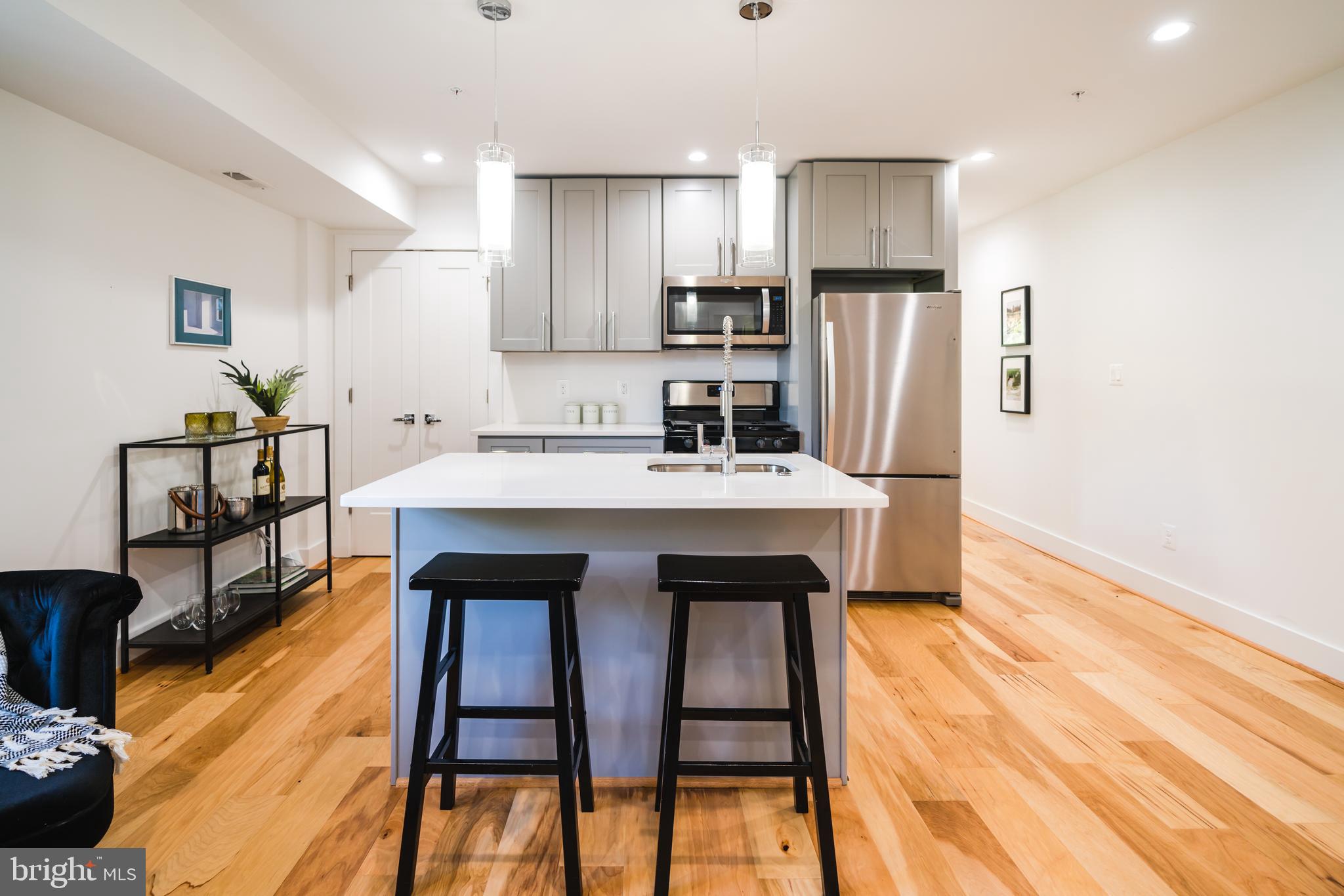 400 Newcomb Street Southeast, Unit 6 Washington, DC 20032 - Photo 8 of 29 a kitchen with stainless steel appliances kitchen island granite countertop a dining table chairs sink and cabinets