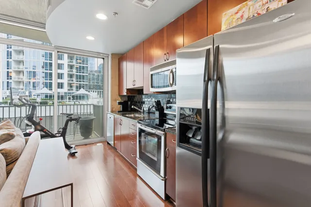 a kitchen with stainless steel appliances granite countertop a refrigerator a stove and a sink with wooden floor