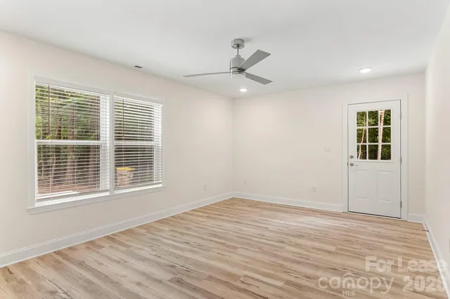 a view of an empty room with wooden floor and a window