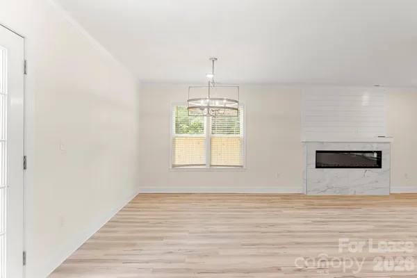 a view of an empty room with wooden floor and window