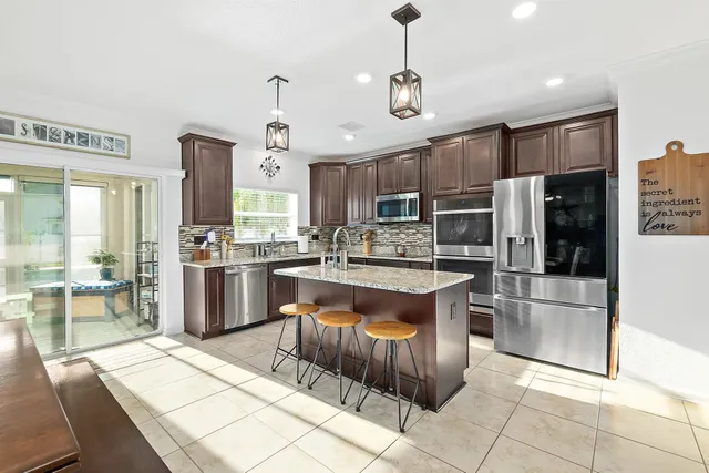 a large kitchen with stainless steel appliances kitchen island granite countertop a refrigerator a stove a sink a table and chairs