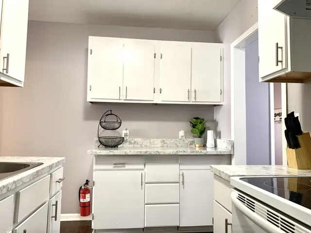 a kitchen with granite countertop white cabinets and white appliances
