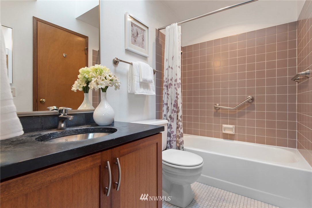 723 North 87th Street Seattle, WA 98103 - Photo 14 of 29 a bathroom with a granite countertop sink a toilet and bathtub