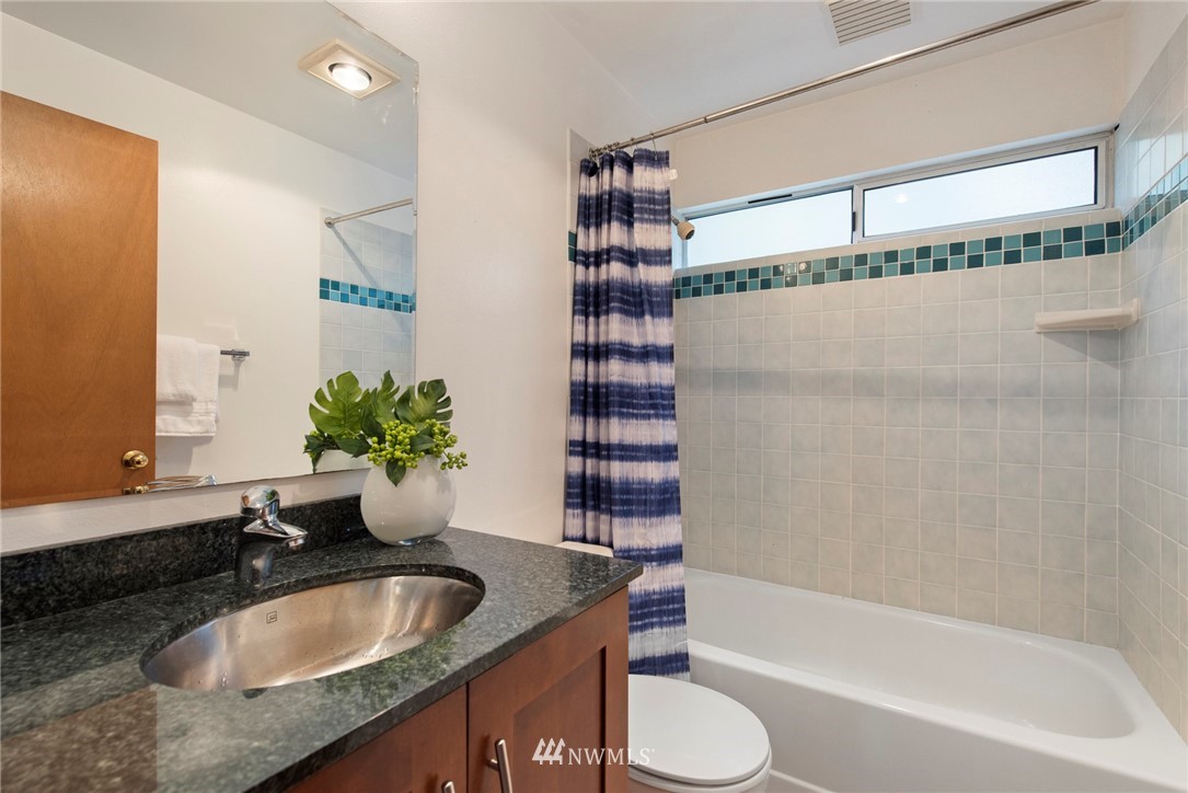 723 North 87th Street Seattle, WA 98103 - Photo 19 of 29 a bathroom with a granite countertop sink and a bathtub