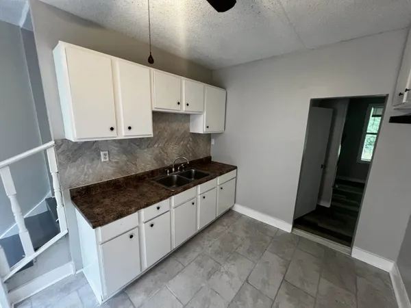 a kitchen with granite countertop a stove and white cabinets