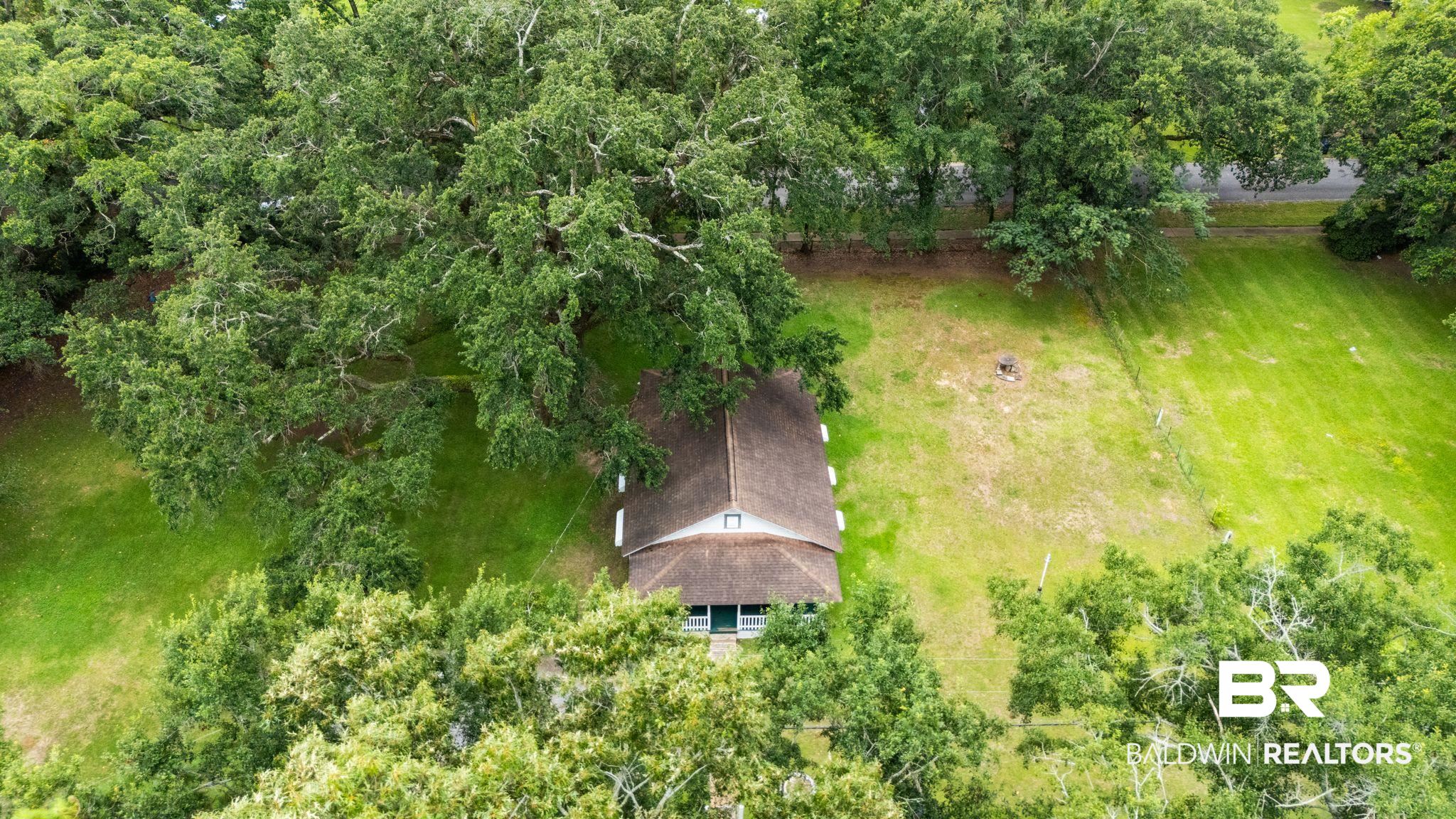 615 West Section Avenue Foley, AL 36535 - Photo 32 of 40 Gable roof home featuring a covered front porch and green siding, surrounded by mature trees and expansive lawn areas