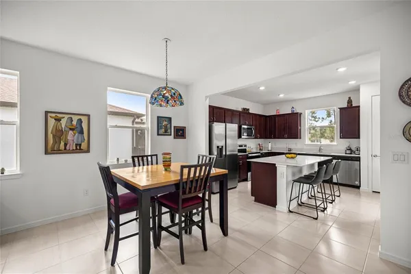 a dining hall with a dining table chairs and kitchen view