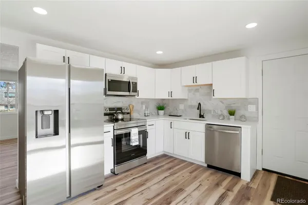 a kitchen with granite countertop white cabinets and stainless steel appliances