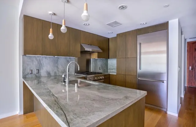 a kitchen with stainless steel appliances granite countertop a sink a refrigerator and a stove