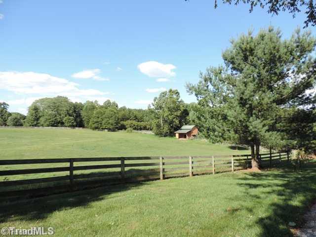5811 Billet Road Oak Ridge, NC 27310 - Photo 2 of 16 The long lane into the heart of Joyfield Farm is lined with granddaddy sycamores mixed with large evergreens. Four board fencing delineates the perimeter. One of two barns.