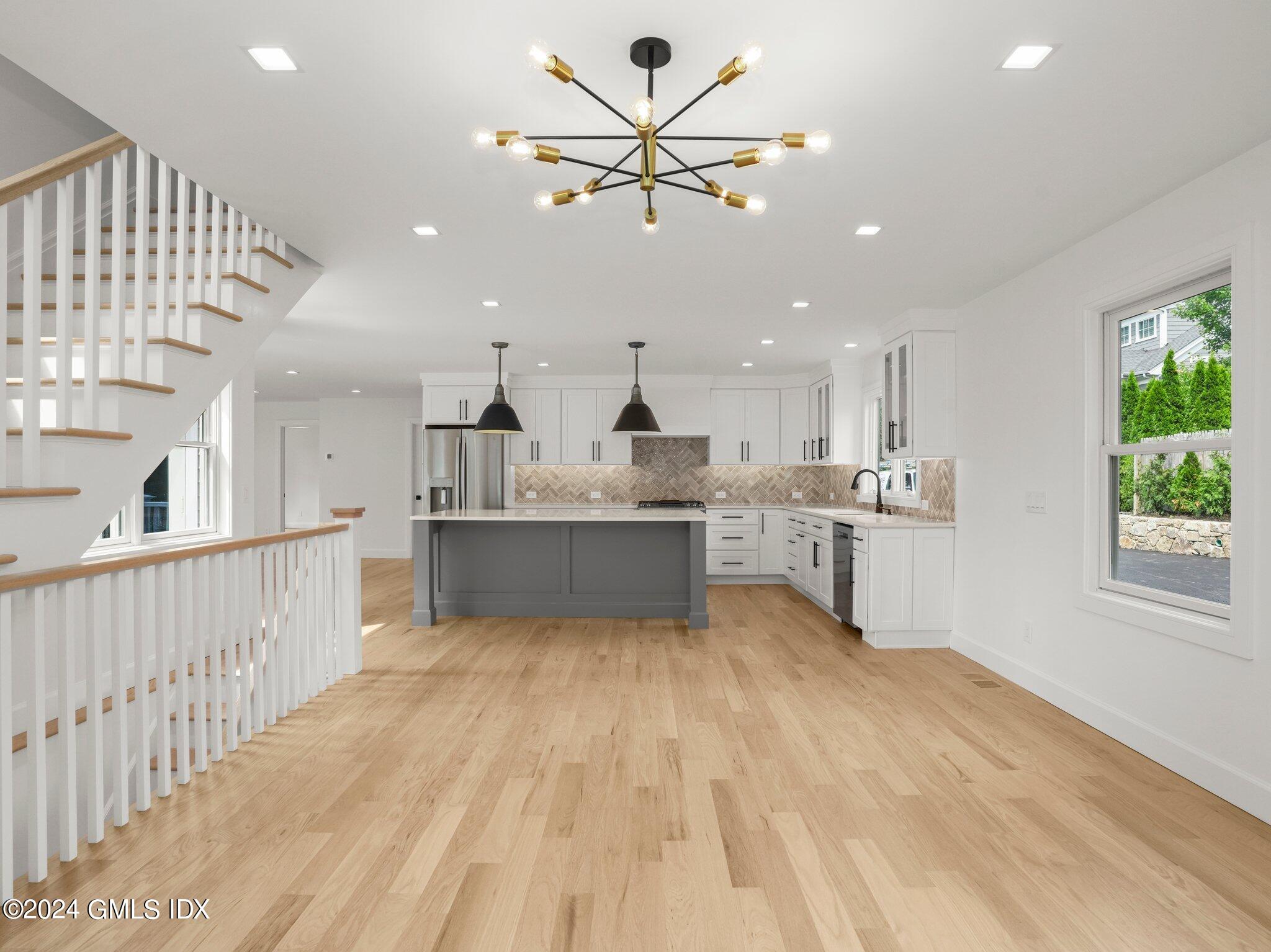 14 Rockland Place Greenwich, CT 06831 - Photo 25 of 54 a large white kitchen with kitchen island a stove a sink dishwasher and a fireplace with wooden floor