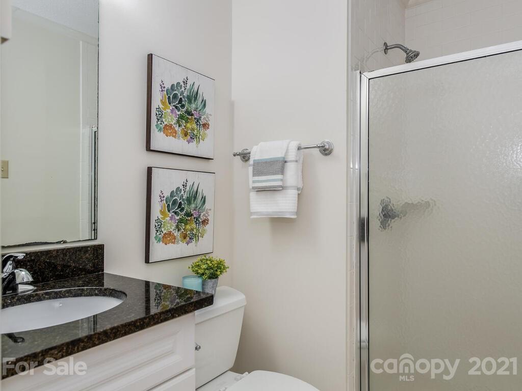4920 Pine Ridge Road Charlotte, NC 28226 - Photo 24 of 28 a bathroom with a granite countertop sink a toilet and a shower