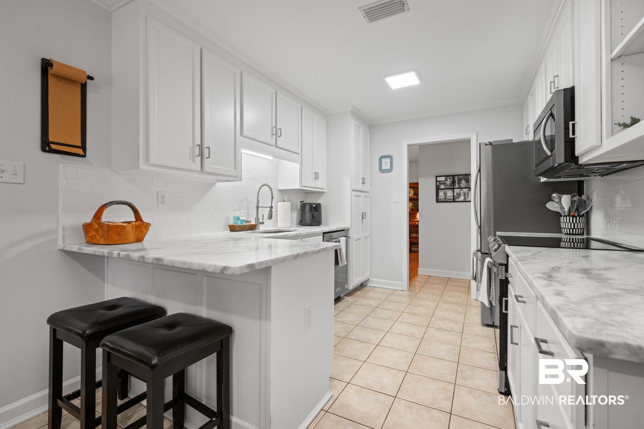 5936 Lundy Road Theodore, AL 36582 - Photo 7 of 32 Galley kitchen featuring white cabinetry, light-toned tiled flooring, white subway tile backsplash, and light-toned countertops