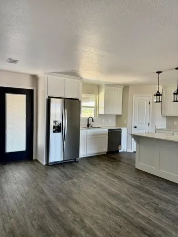 a view of a kitchen with stainless steel appliances refrigerator sink and cabinets