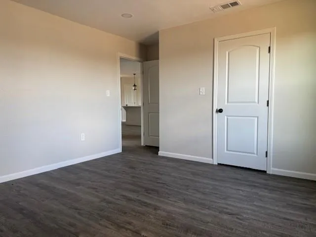 a view of an empty room with wooden floor and closet