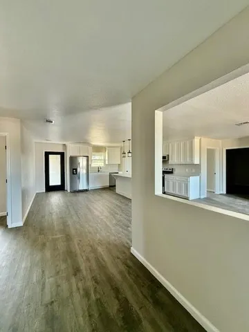 a view of a livingroom with wooden floor and kitchen