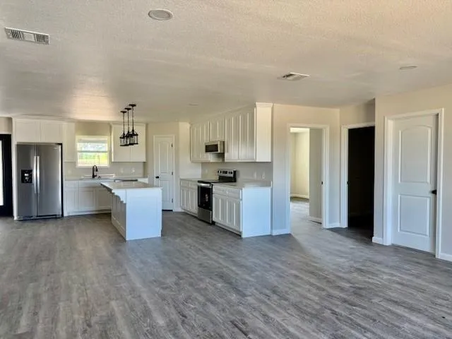 a large kitchen with a center island wooden floor stainless steel appliances and cabinets