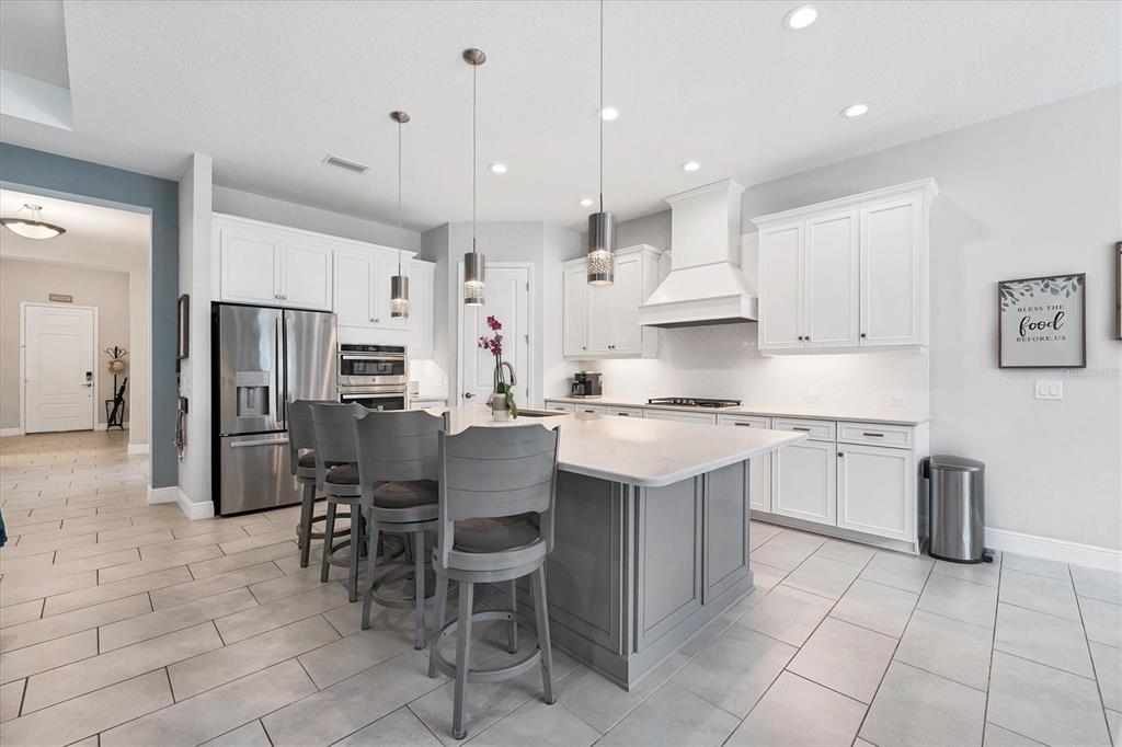13306 Deep Blue Place Bradenton, FL 34211 - Photo 5 of 73 a kitchen with stainless steel appliances granite countertop a sink a stove a refrigerator and white cabinets with wooden floor