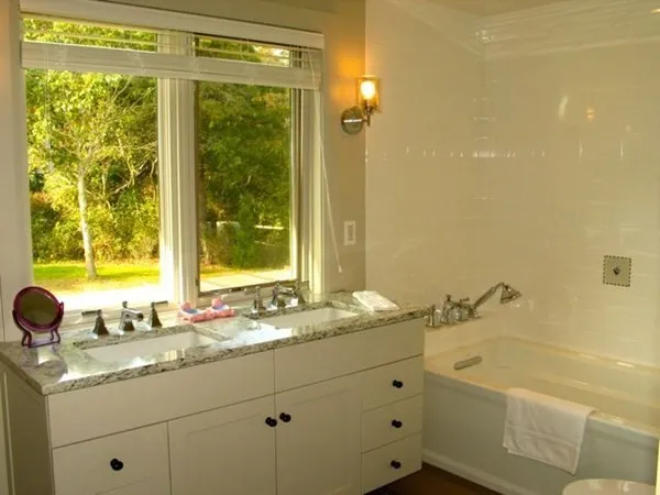 a bathroom with a granite countertop sink mirror and a bathtub