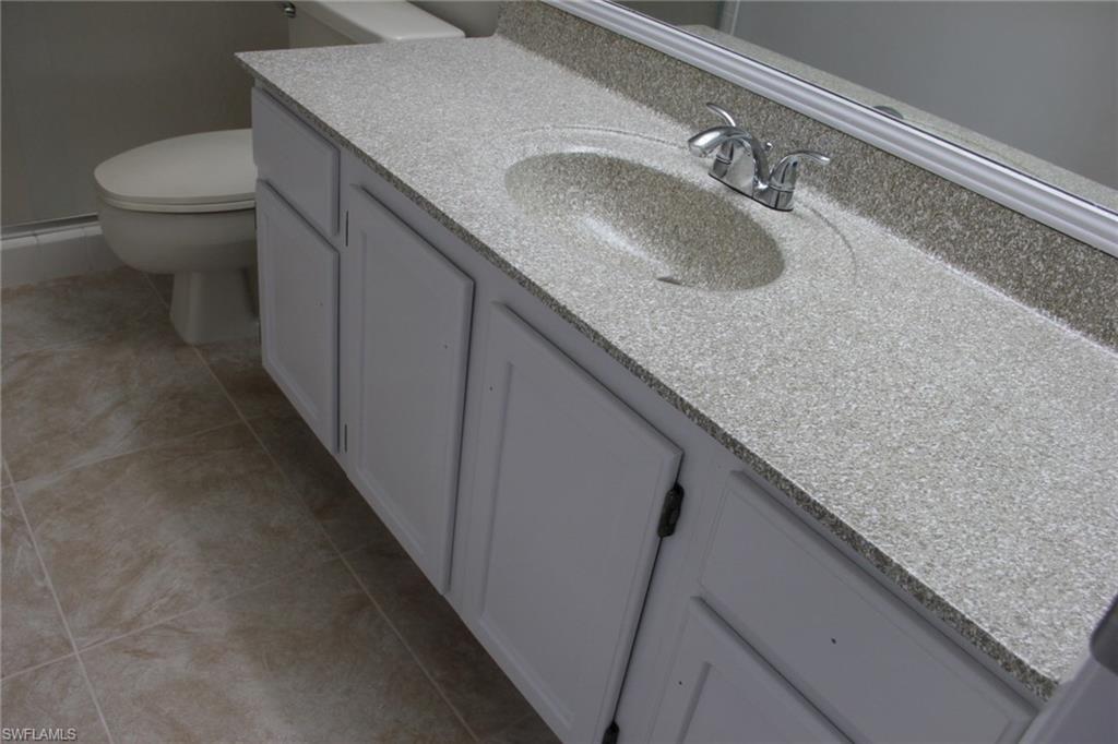 5841 Rattlesnake Hammock Road, Unit I206 Naples, FL 34113 - Photo 12 of 24 a bathroom with a granite countertop sink and a toilet