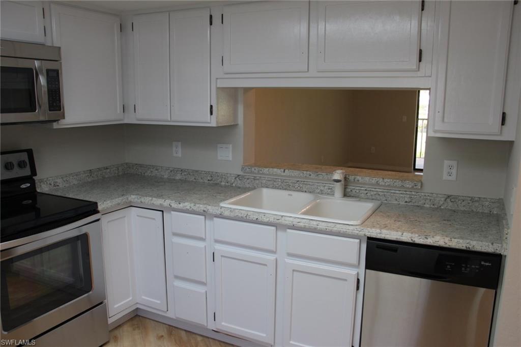 5841 Rattlesnake Hammock Road, Unit I206 Naples, FL 34113 - Photo 8 of 24 a kitchen with white cabinets and sink
