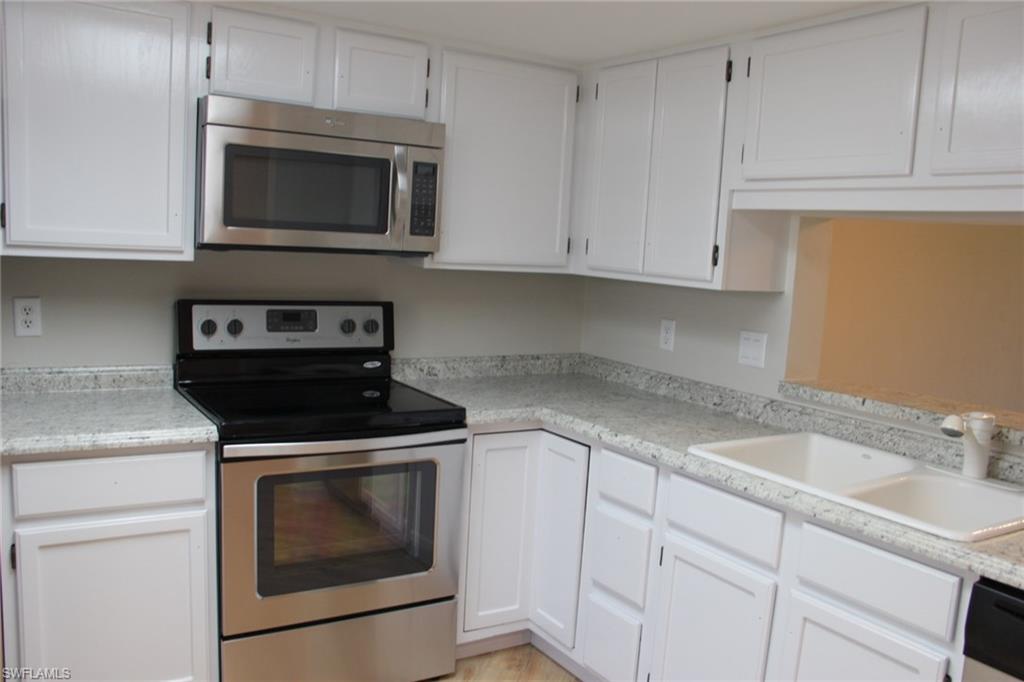 5841 Rattlesnake Hammock Road, Unit I206 Naples, FL 34113 - Photo 9 of 24 a kitchen with granite countertop white cabinets and stainless steel appliances