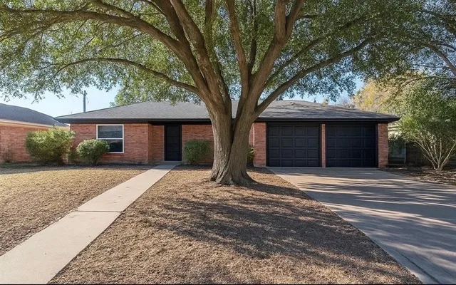a front view of a house with a garden and trees