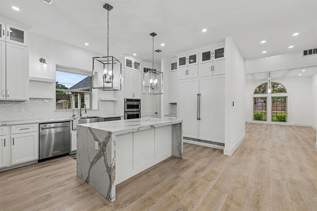 17327 Davenport Road Dallas, TX 75248 - Photo 19 of 40 a large kitchen with stainless steel appliances kitchen island granite countertop a stove a sink a refrigerator and white cabinets with wooden floor