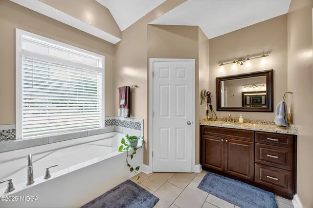 a spacious bathroom with a tub a mirror and a sink