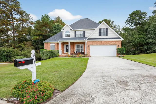 a front view of a house with a yard and potted plants