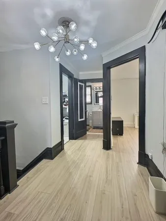 a view of an empty room with wooden floor and a kitchen