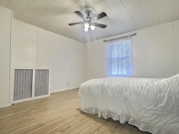 a bed sitting in a spacious bedroom next to a window and a chandelier