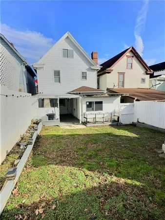 a view of a white house with a yard patio and a small yard