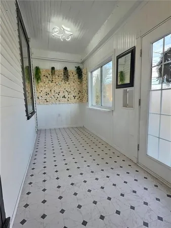 a view of a hallway to a window with wooden floor