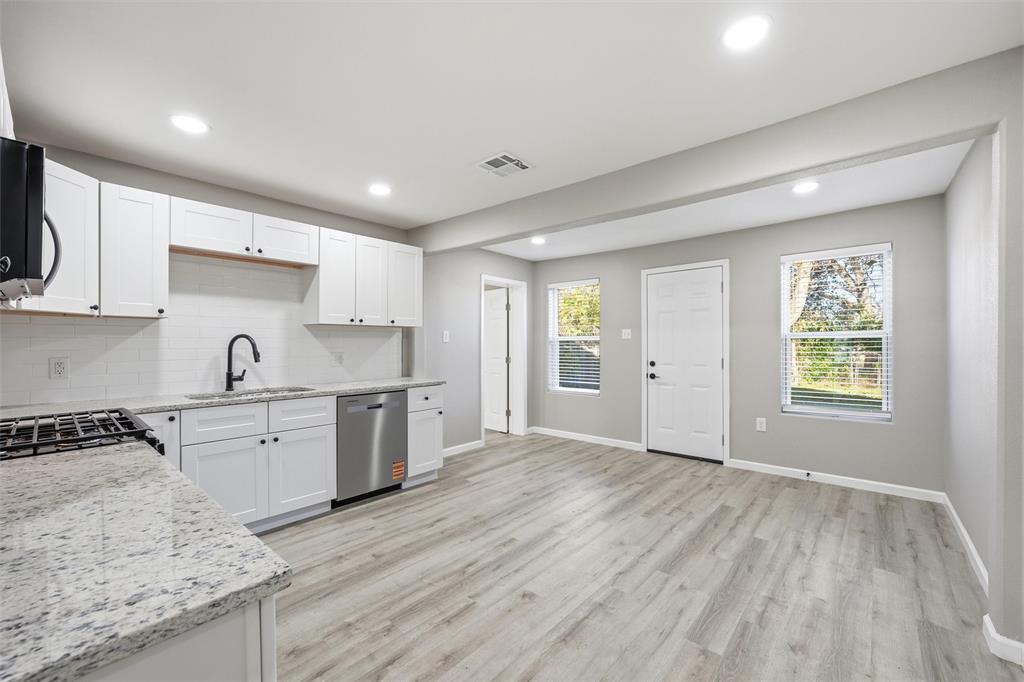 803 Garrison Street Waco, TX 76704 - Photo 6 of 16 a kitchen with granite countertop a stove a sink dishwasher and a refrigerator with wooden floor