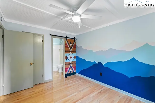 a view of a bedroom with a bed and wooden floor