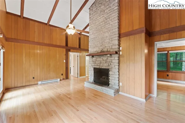 an empty room with wooden floor fireplace and windows